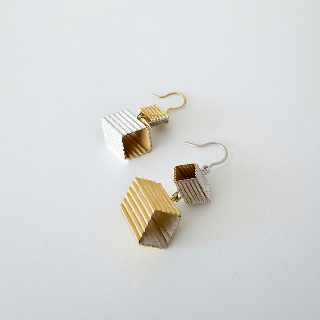 Ces boucles d’oreilles asymétriques en argent et vermeil montrent un design en formes d'escalier et finitions inversées.