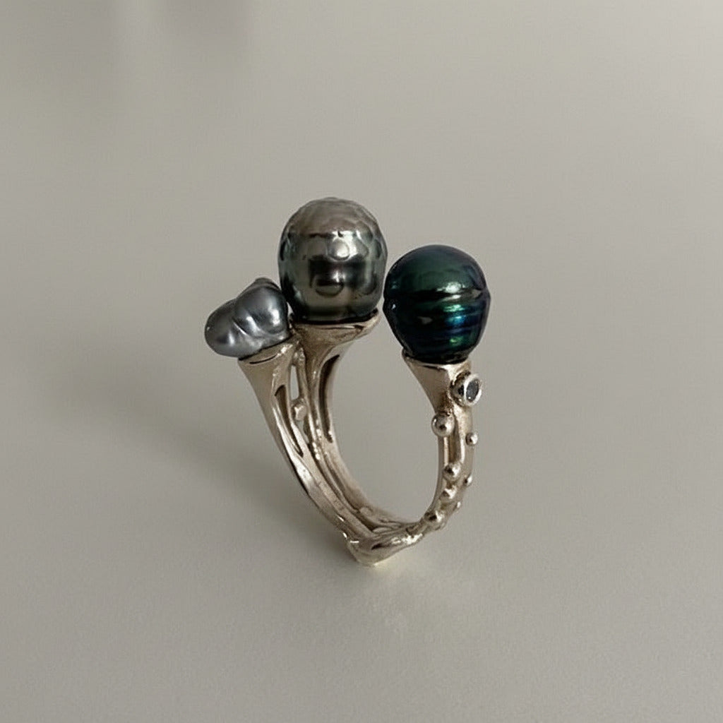 Bague ouverte présentant deux perles de Tahiti sculptée,de couleurs différentes et une perle keshi carrée.L'anneau en argent est orné de petites pierres de couleurs. Une pièce réalisée à la main par Ivan Michelson.