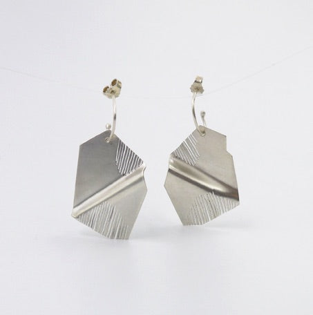 Une paire de boucles d'oreilles pendentes en argent découpé par endroit. Fait à la main en France.