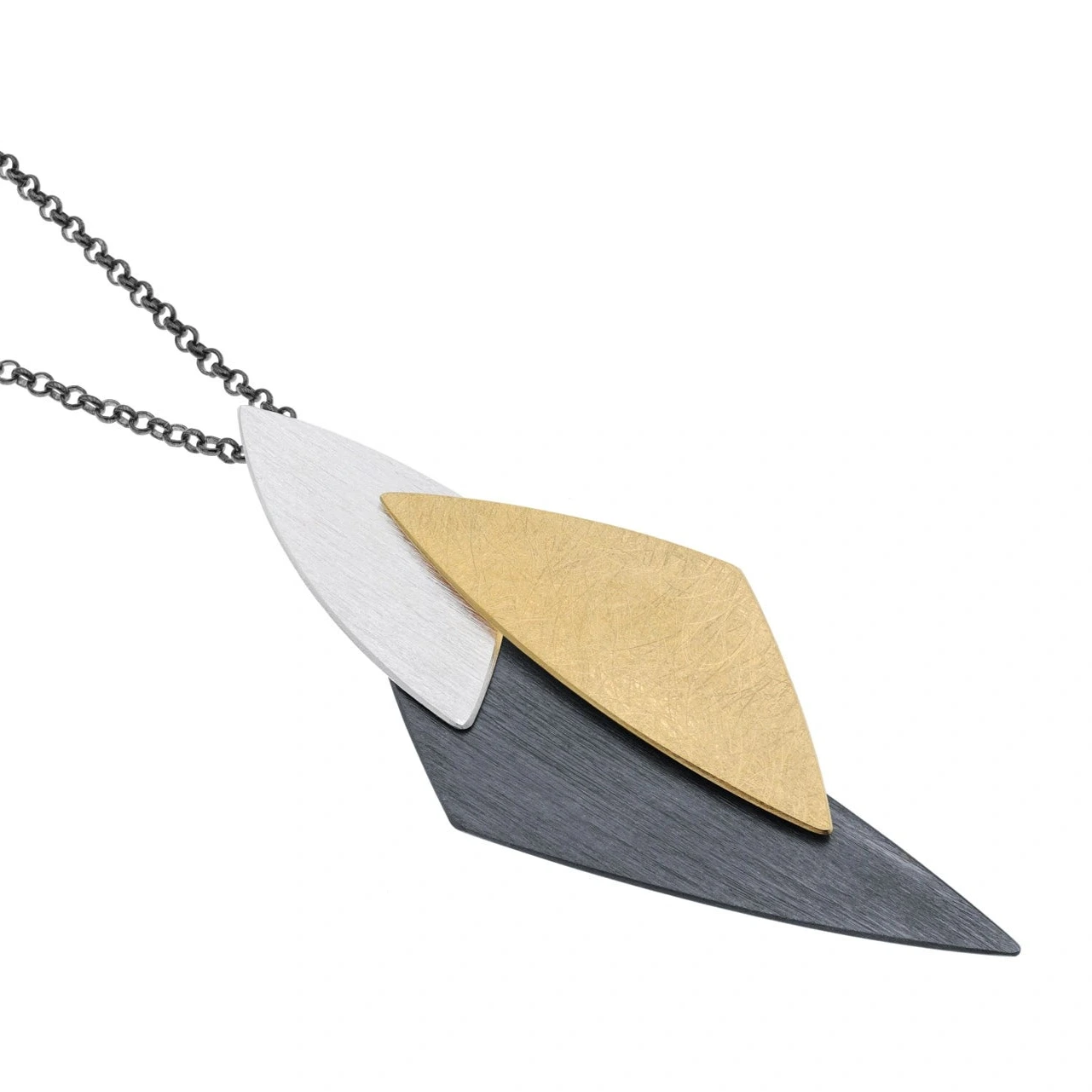 Ce pendentif géométrique articulé est composé de trois triangles de tailles et finitions variées: l'argent brossé, oxydé et plaqué or jaune. Il est monté sur une chaîne patinée noire.