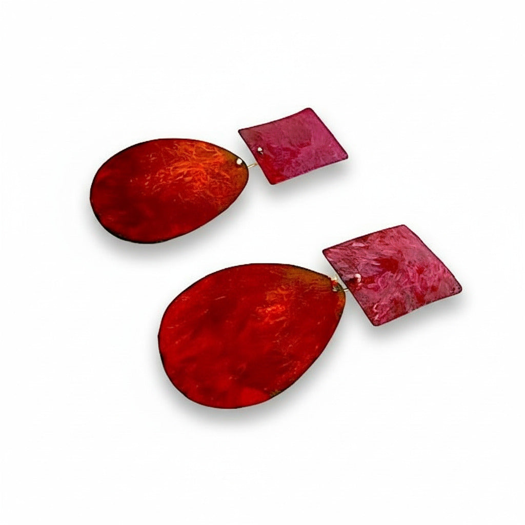 Ces boucles géométriques XL associent un ovale brun orangé à un carré fuchsia . Modernes et légères elles sont peintes à la main par la créatrice Dora Haralambaki.