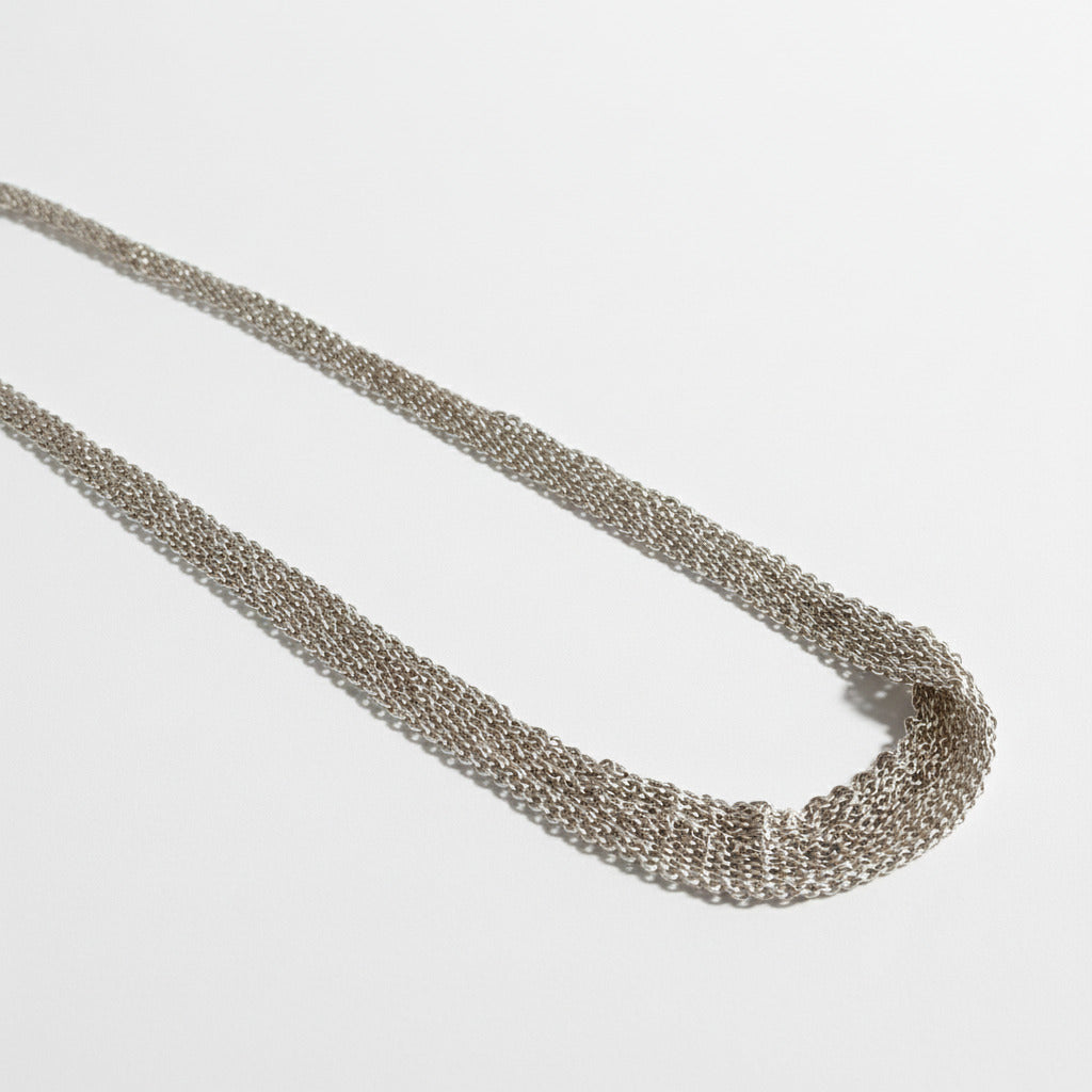 Tour de cou dégradé composé de plusieurs chaînes en argent assemblées ensemble au fil de soie. Un collier délicat fait entièrement à la main par l'artiste belge Ria Lins.