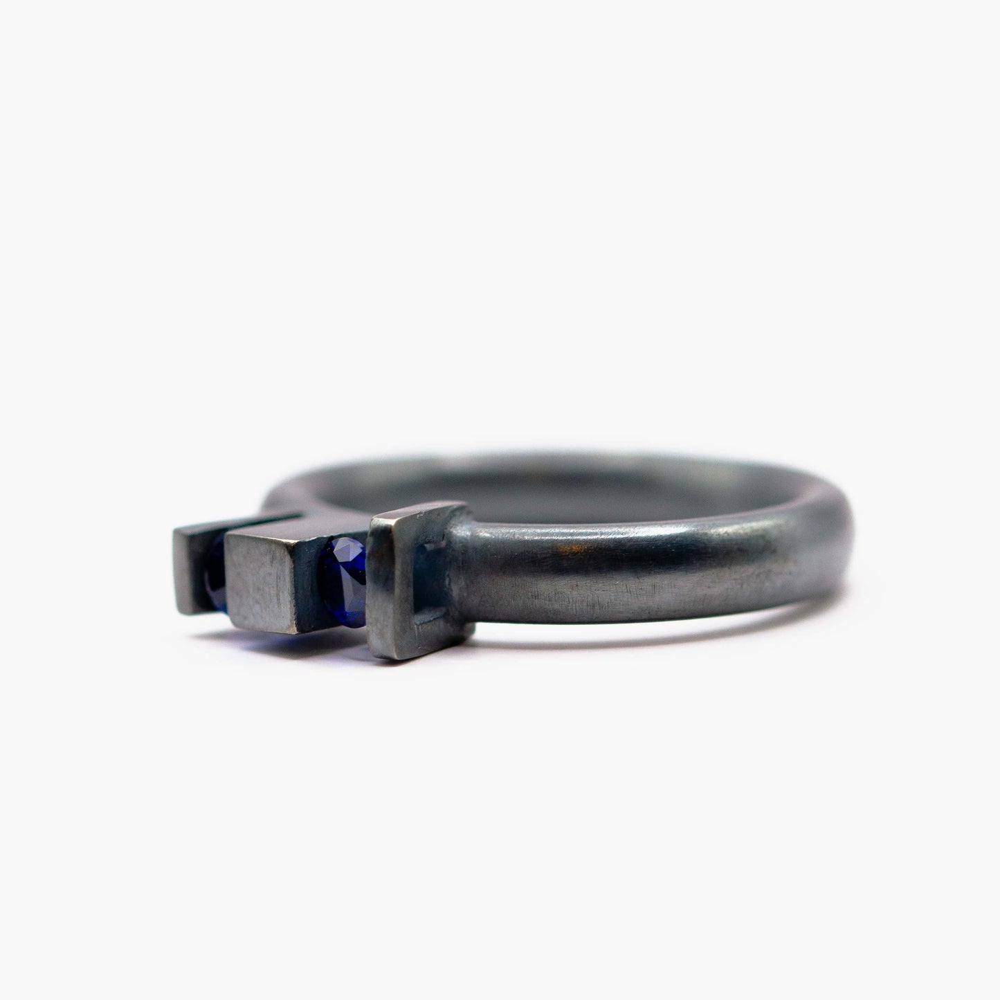 Bague géométrique Skyline en argent forgé et oxydé, ornée de deux saphirs de culture bleus sertis dans des volumes architecturaux.
