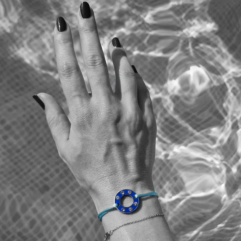 Bracelet Ready-Made en rondelle d'aluminium bleu et six saphirs blancs, présenté sur lien de coton ciré bleu. vue portée