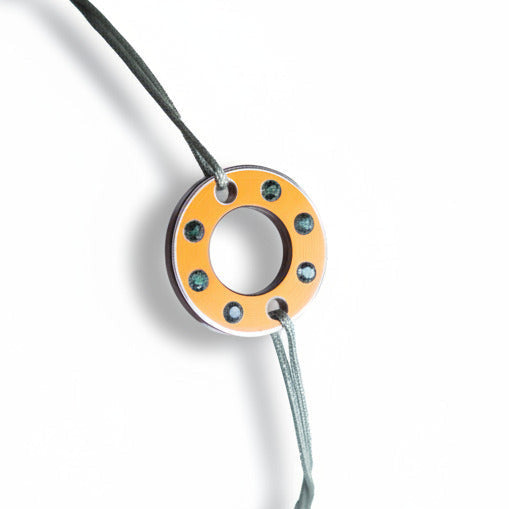 Bracelet Ready-Made petit modele composé d'une rondelle en aluminium orange, sertie de six tourmalines vertes. Un bracelet contemporain et unisexe présenté sur lien de coton ciré.