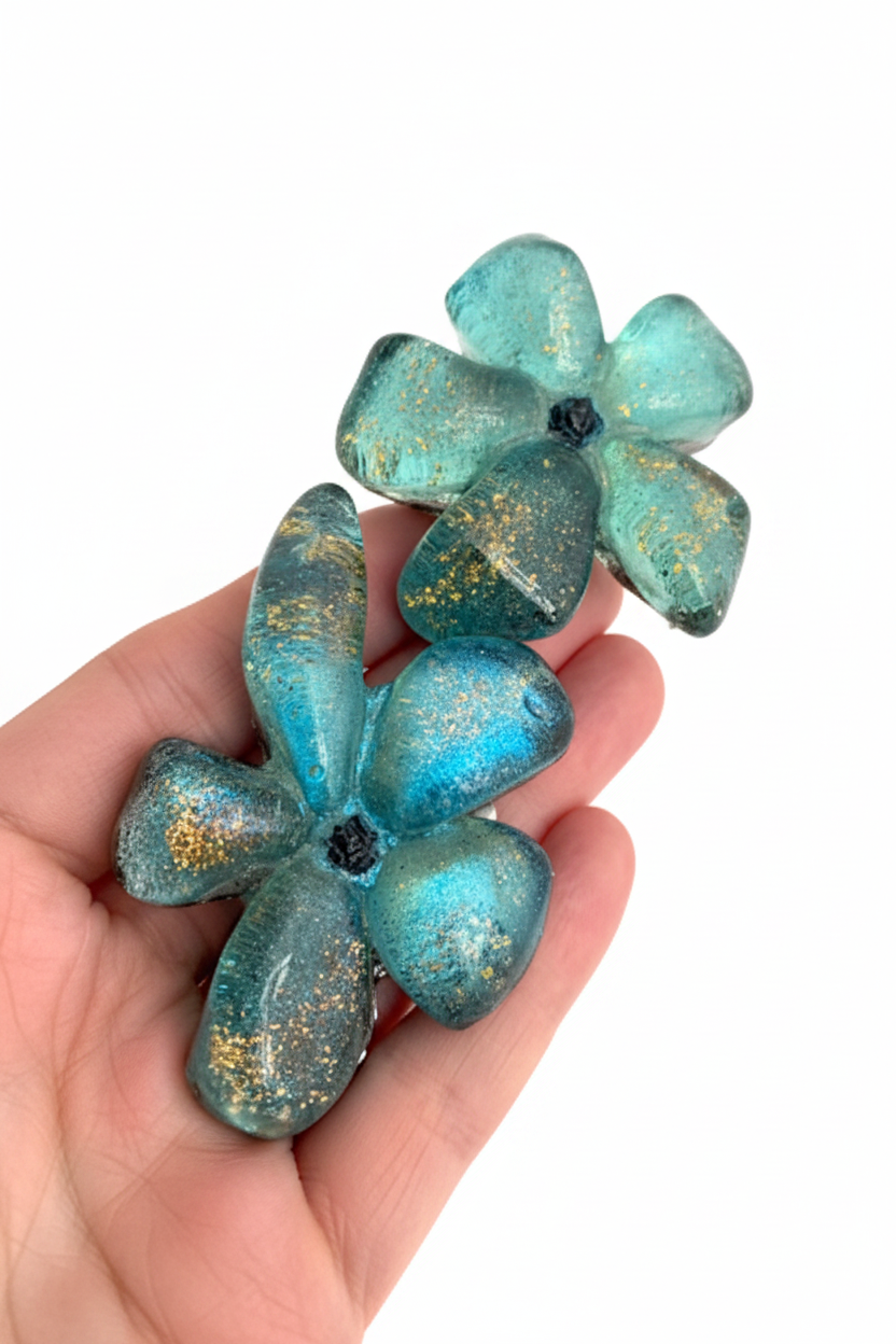 Collier en résine bleu vert avec reflets irisés, cable acier noir. Fermoir aimanté à l'avant inséré dans les fleurs.
