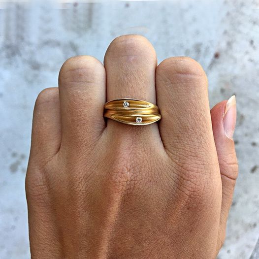 Bague inspirée par un coquillage en argent ornée de 3 plis avec intérieur plaqué or 22 carats, 2 diamants sont sertis en diagonale dans les creux. Bijou sur main pliée.