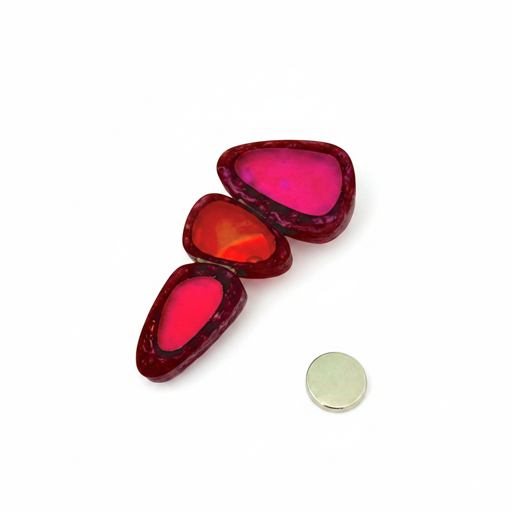 Broche façonnée de 3 éléments en résine irisée dans les tons rouge/fushia. Fermoir aimanté.