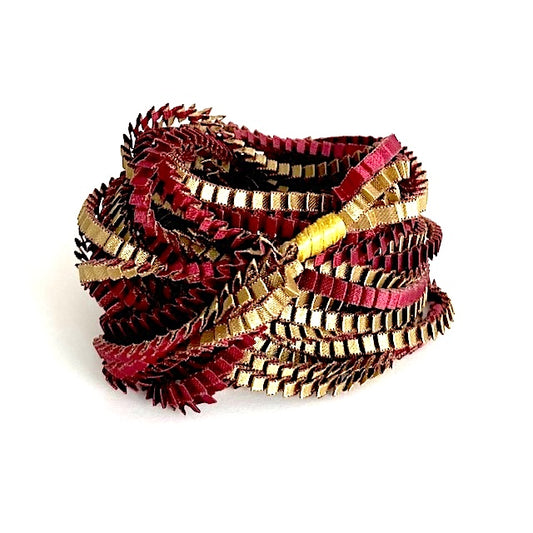 Long sautoir de couleur olive et bordeaux composé de huit bandes de satin plissé reliées les unes aux autres par un lien de coton jaune.