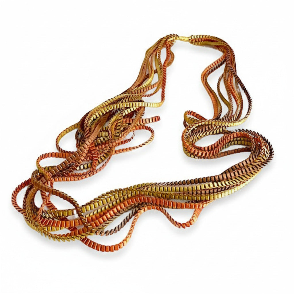 Long sautoir de couleur marron, doré, cuivré composé de huit bandes de trois millimètres de satin plissé reliées les unes aux autres par un lien de coton jaune d'or.