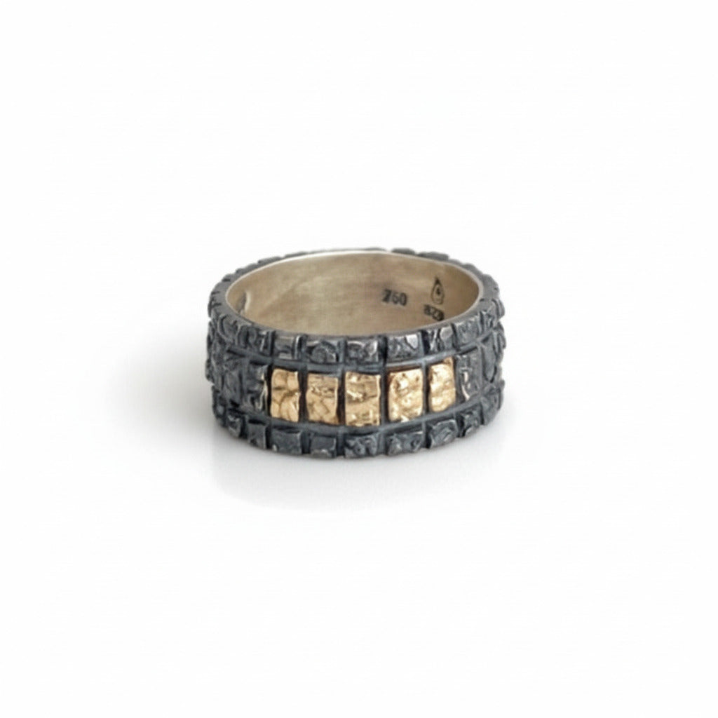 Anneau large au design géométrique en argent patiné avec cinq carrés en or jaune alignés sur le dessus de la bague. 