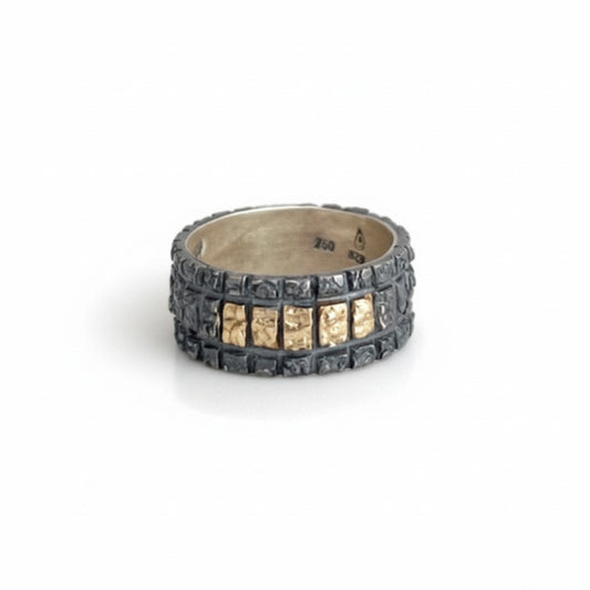 Anneau large au design géométrique en argent patiné avec cinq carrés en or jaune alignés sur le dessus de la bague. 