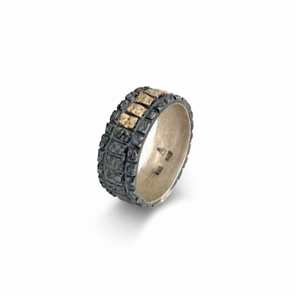Anneau large au design géométrique en argent patiné noir avec cinq carrés en or jaune alignés sur le dessus de la bague. 