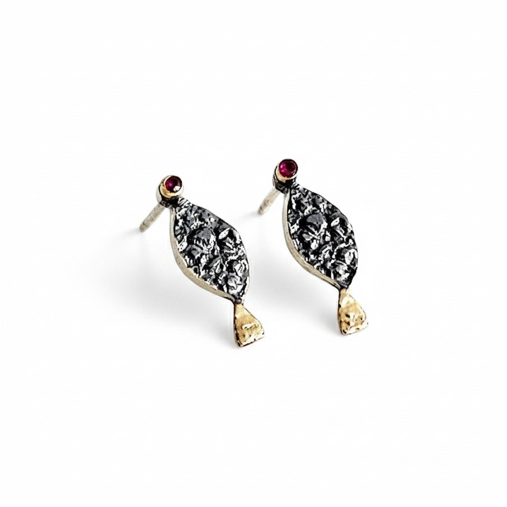 Clous d'oreilles en forme de petit poisson stylisé. La tête est ornée d'un rubis serti sur le lobe, le corps en argent patiné et texturé, la queue se pare d'or jaune. 