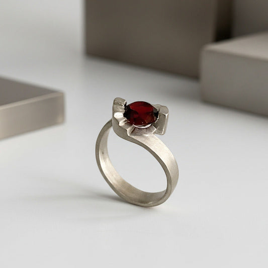 Un solitaire contemporain aux lignes architecturales, inspiré des escaliers en colimaçon. En argent brossé serti d'un grenat facetté, la bague Pas de Deux est signée Lucien Grandval.