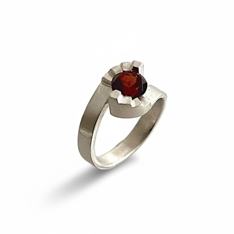 Bague contemporaine aux lignes architecturales, inspiré des escaliers en colimaçon. En argent brossé serti d'un grenat facetté, la bague Pas de Deux est signée Lucien Grandval.