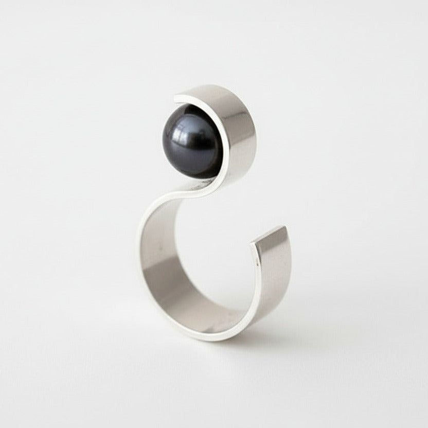 Bague contemporaine en forme de S avec finitions argent poli et brossé, une perle noire de Tahiti orne ce bijou.
