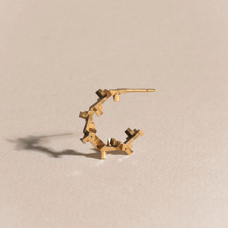 Boucle d’oreille design minimaliste formant un octogone. Détail des arêtes polies et intérieur sablé.