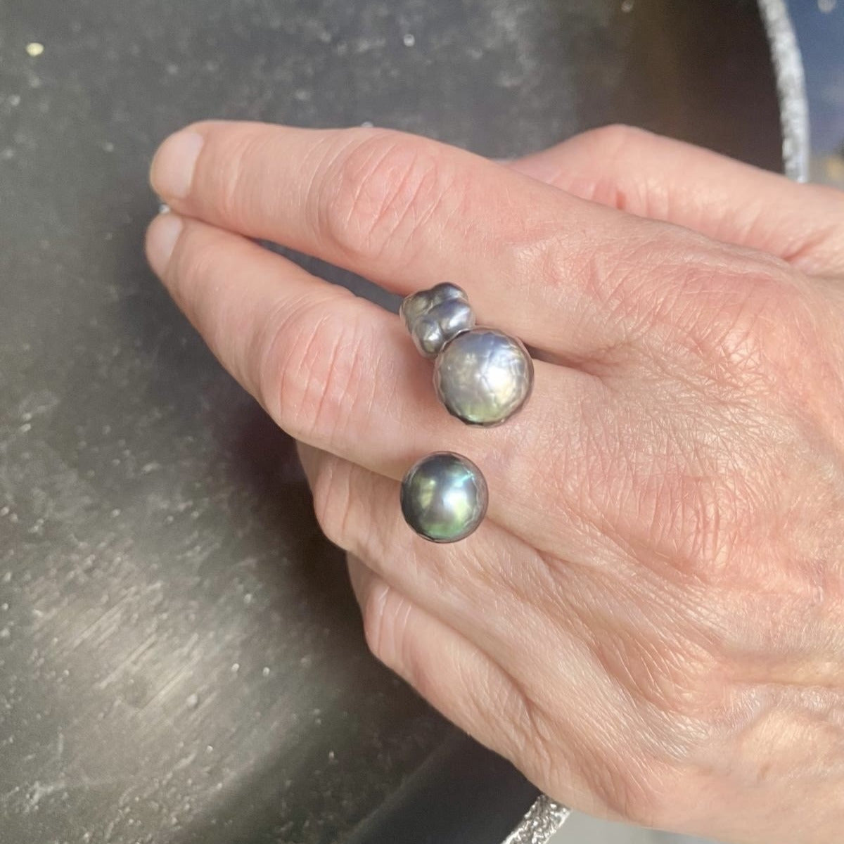 Bague ouverte présentant deux perles de Tahiti  sculptée,de couleurs différentes et une perle keshi carrée.L'anneau en argent est orné de petites pierres de couleurs.