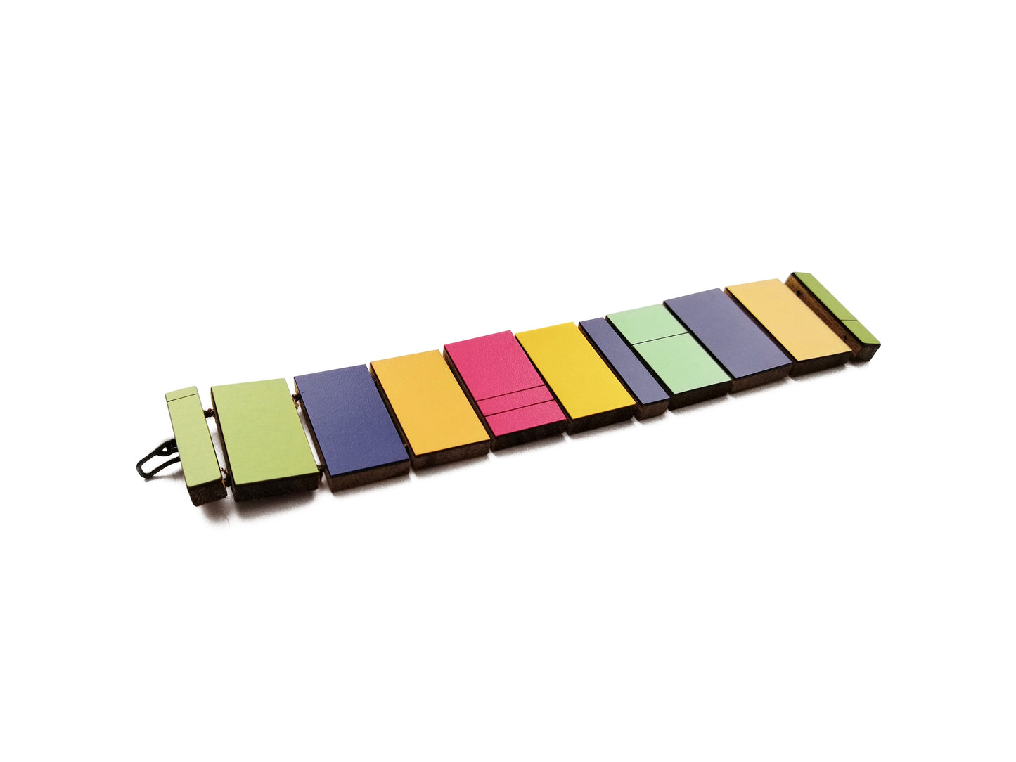 Bracelet design en bois et formica multicolore avec fermoir en argent patiné noir. Il se compose de 11 rectangles de différentes tailles kaki, beu foncé, jaune, rose foncé, vert, beige.Détail du bijou à plat sur fond blanc.