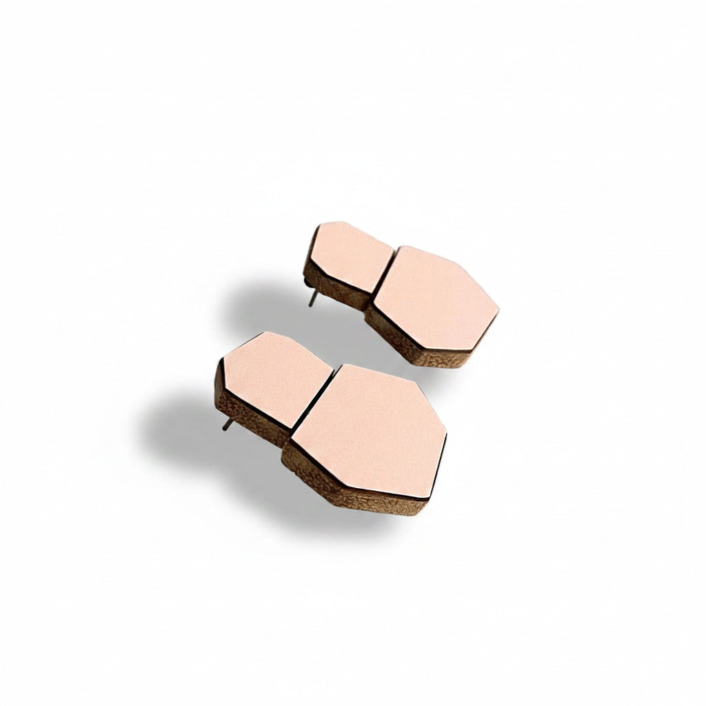 Boucles d'oreilles de forme géométrique en bois recouvert de formica rose pâle. Finition mat. Vue de profil.