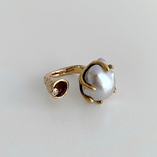 Bague ouverte, forme "Toi et Moi" en bronze ornée d'une perle grise baroque sertie par six griffes et d'un diamant taille brilliant.