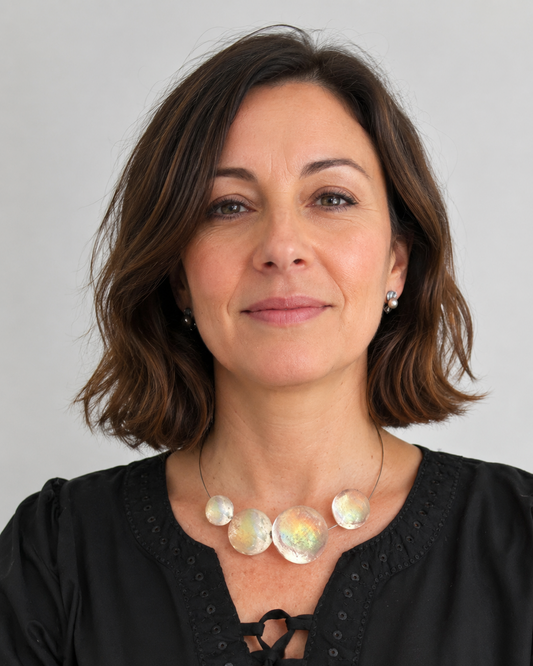 Le collier Météorites se compose de quatre sphères en résine transparente texturée, assemblées sur un câble gris épuré. Le fermoir aimanté est intégré dans deux éléments de résine. Bijou porté.