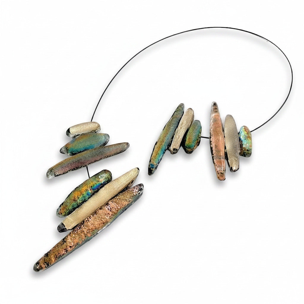 Collier sculptural en résine texturée composé de douze éléments en forme de stalactites dans des tonalités de beige rosé et de vert. Fermoir aimanté.
