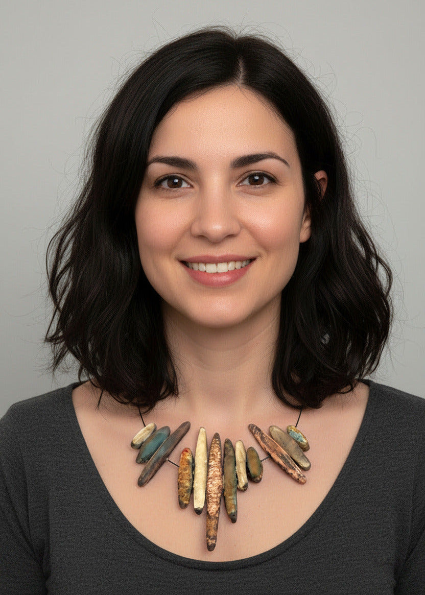 Détails du collier graphique léger inspiré des formes minérales. Cette création artisanale inspirée par des stalactites présente douze éléments en résine texturée irisée. Collier plastron dans des tonalités de beige rosé et de vert. Bijou porté.