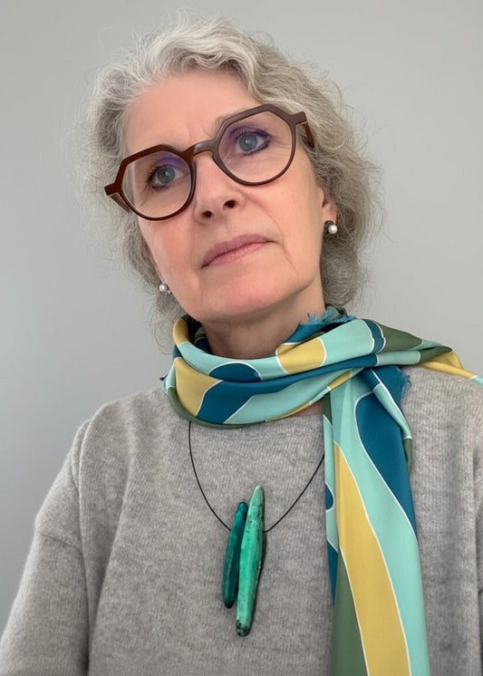 Ce collier contemporain associe deux éléments allongés en résine texturée et irisée, dans des nuances de vert émeraude et céladon. Bijou porté.