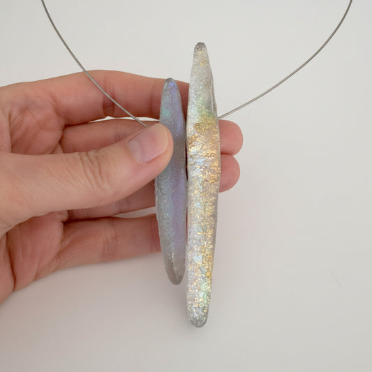 Détail collier graphique en résine opalescente grise sur câble fin. Bijou contemporain artisanal aux reflets subtils, fabrication française et artisanale.