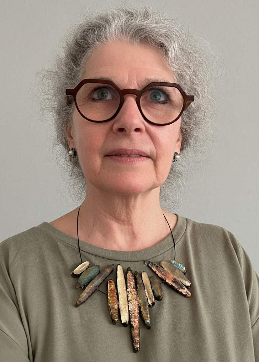 Collier contemporain composé de douze Stalactites de différentes tailles en résine irisée beige rosé et vert sur câble noir. Une création artisanale et française, signé Marianne Olry.