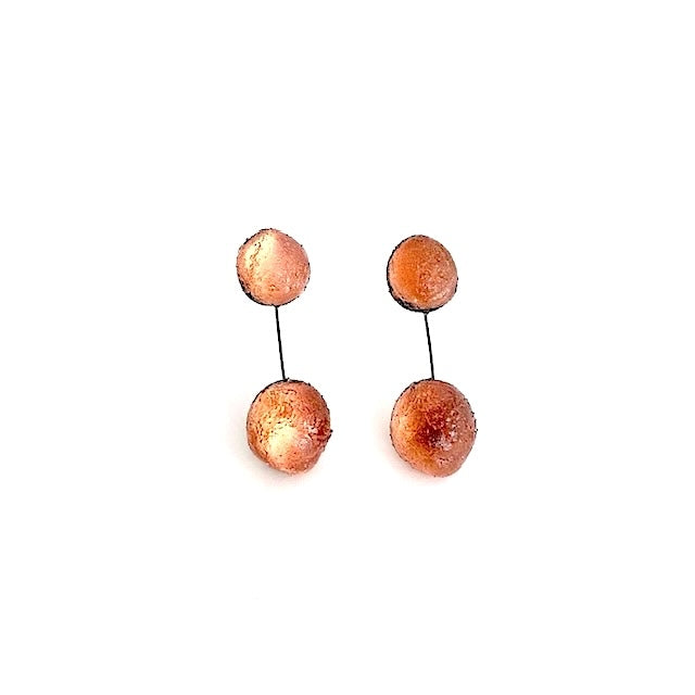  Boucles pendantes composées de deux sphères en résine texturée de couleur ambre, reliées par un câble fin et solide, noir. Pour oreilles percées.