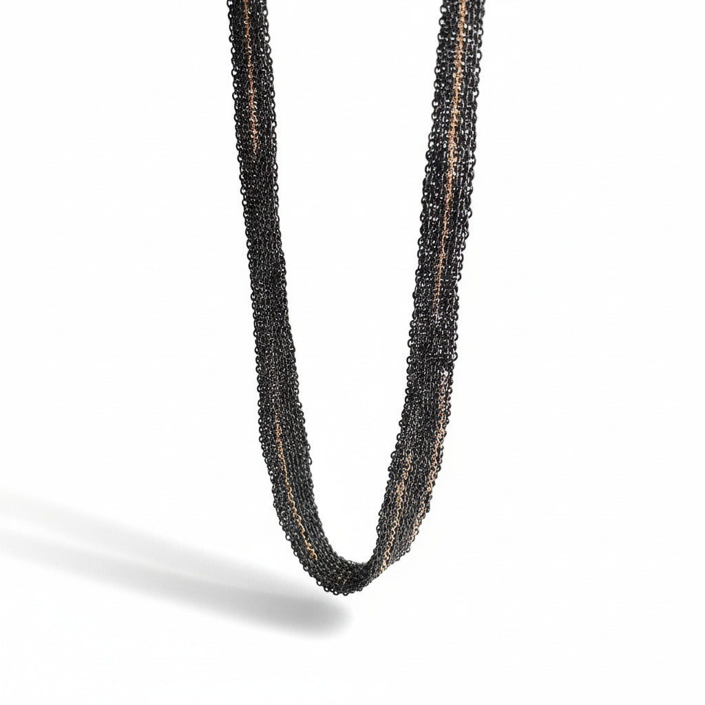 Détails d'un collier léger et confortable en chaînes d'argent oxydé assemblées au fil de soie, avec des détails en chaîne dorée or rose.  Un bijou d'artiste de Ria Lins.