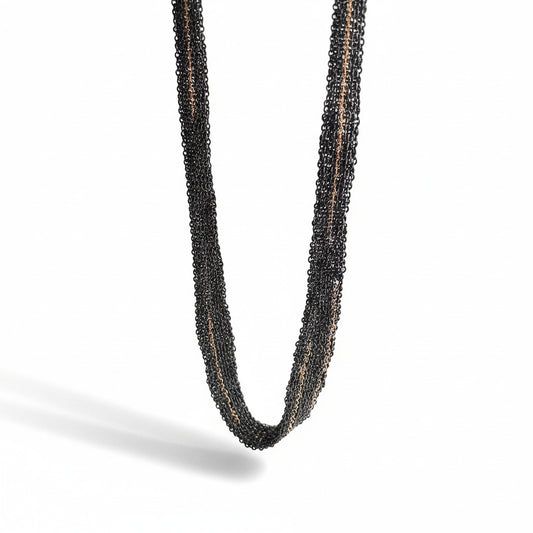 Détails d'un collier léger et confortable en chaînes d'argent oxydé assemblées au fil de soie, avec des détails en chaîne dorée or rose.  Un bijou d'artiste de Ria Lins.