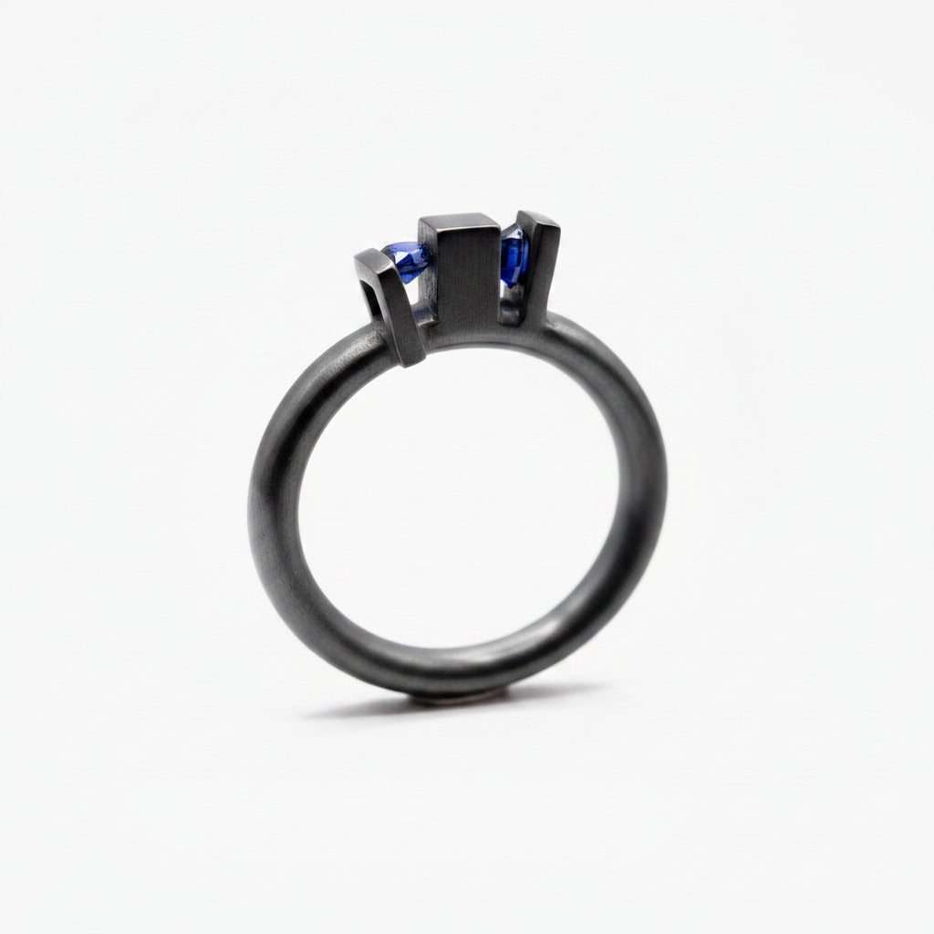 Bague géométrique Skyline en argent forgé et oxydé, ornée de deux saphirs de culture bleus sertis dans des volumes architecturaux.