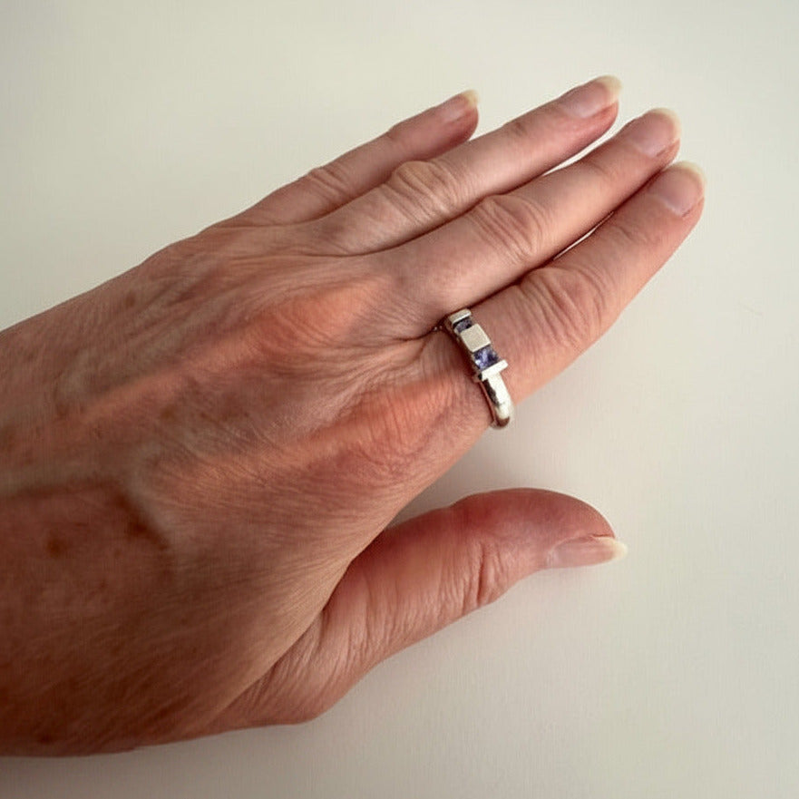 Une bague aux lignes architecturales,. Son anneau rond met en valeur deux volumes verticaux qui accueillent deux tanzanites bleues et facettées. Bijou signé Stefanie Verhoef, artiste néerlandaise-danoise.