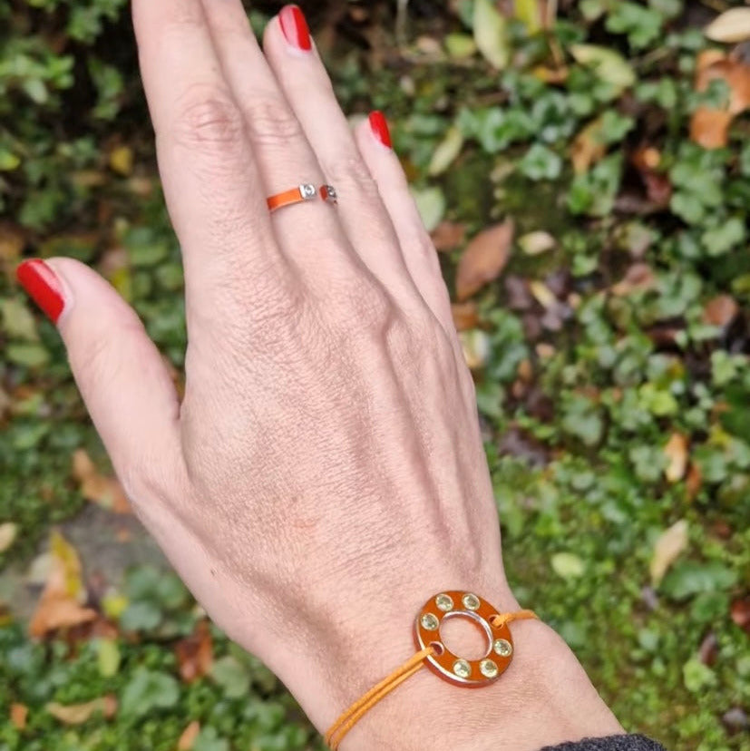 Bracelet Ready-Made en rondelle d'aluminium orange, sertie de  six péridots. Un bracelet design, présenté sur lien de coton ciré orange. vue portée