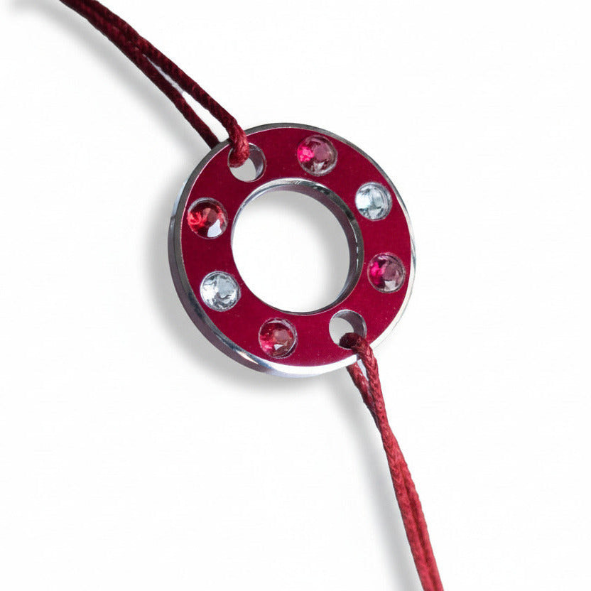 Bracelet Ready-Made, rondelle d'aluminium rouge sertie de  quatre spinelles rouge et deux aigue-marines. Un bracelet contemporain et unisexe présenté sur lien de coton ciré rouge. 