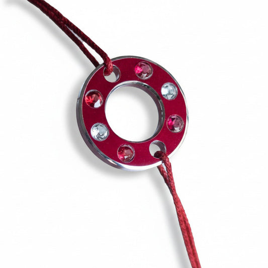 Bracelet Ready-Made, rondelle d'aluminium rouge sertie de  quatre spinelles rouge et deux aigue-marines. Un bracelet contemporain et unisexe présenté sur lien de coton ciré rouge. 