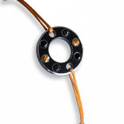 Bracelet Ready-Made, rondelle d'aluminium noir sertie de  quatre spinelles noirs et deux saphirs oranges. Un bracelet contemporain et unisexe présenté sur lien de coton ciré orange. 