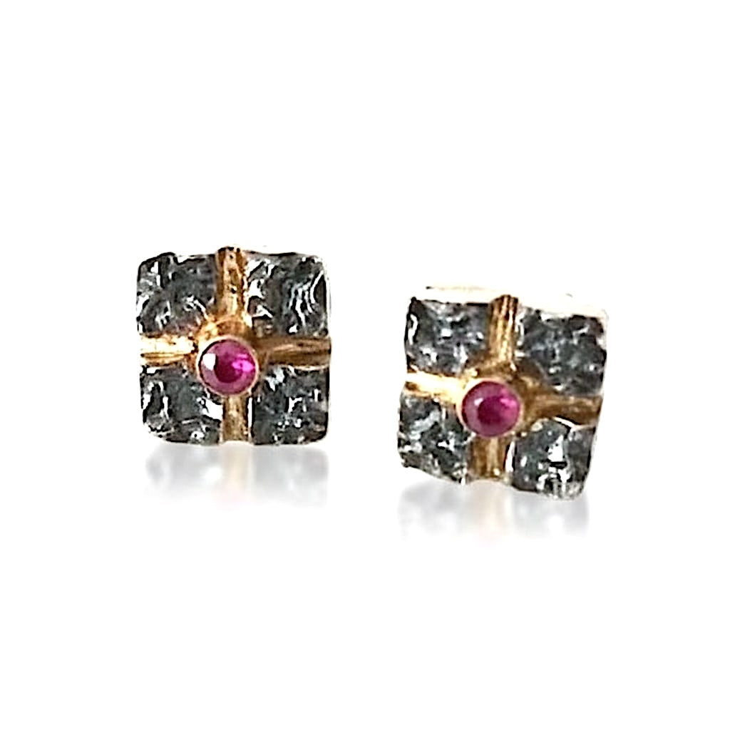 Clous d'oreilles carrés en argent texturé, et oxydé entrecroisés par 2 lignes or jaune, au centre un rubis. Un bijou moderne et élégant fait à la main par l'artisan joaillier Apostolos kleitsiotis.
