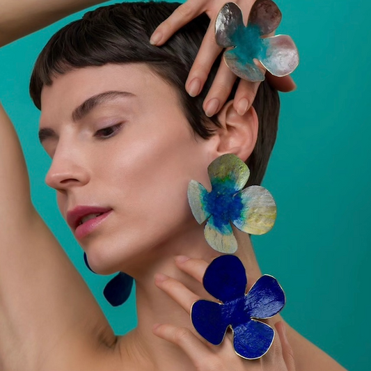Bagues et boucles d'oreilles grandes fleurs peintes à la main dans les tons de bleus. Bijoux portés.