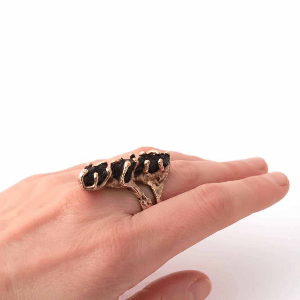 Bague contemporaine en bronze de forme allongée sertie de trois tourmalines noires. Détail de la bague portée.