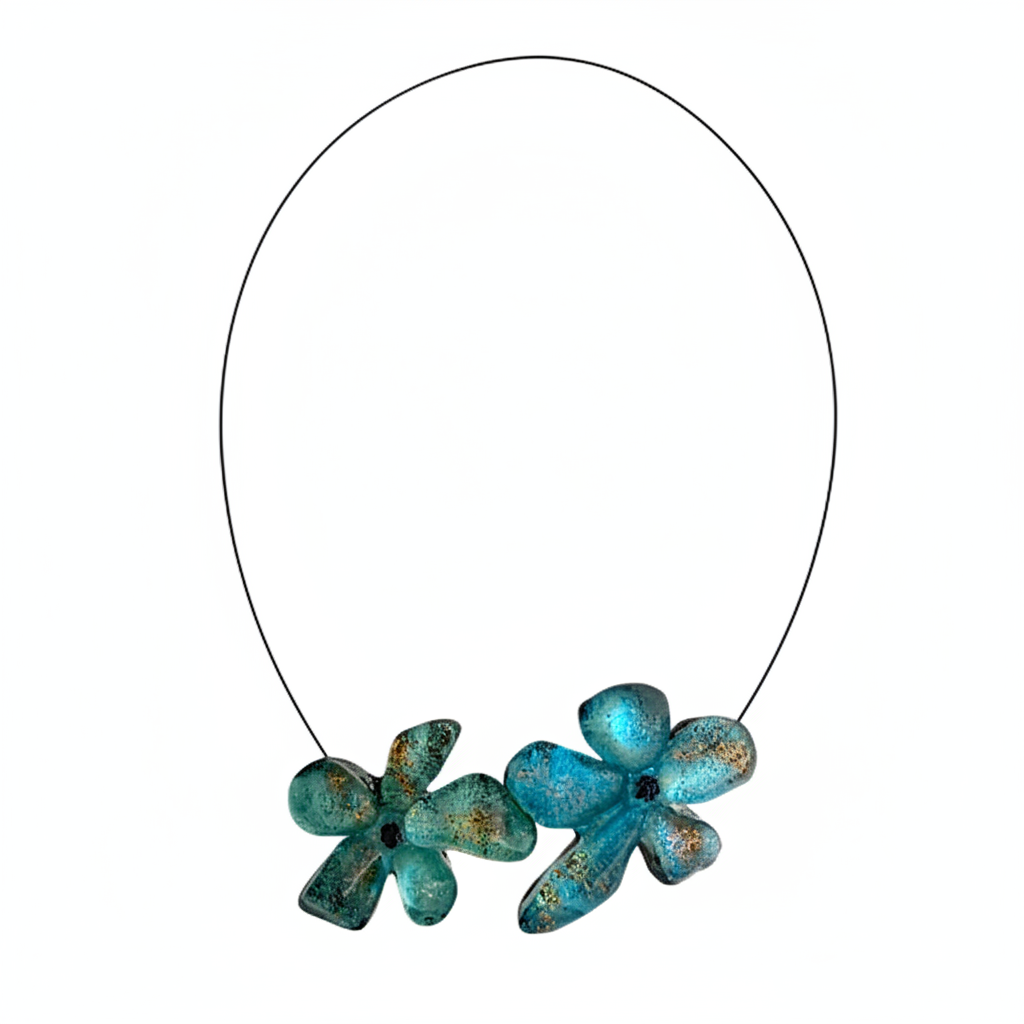 Collier en résine bleu vert avec reflets irisés, cable acier noir. Fermoir aimanté à l'avant inséré dans les fleurs. Fabrication artisanale.