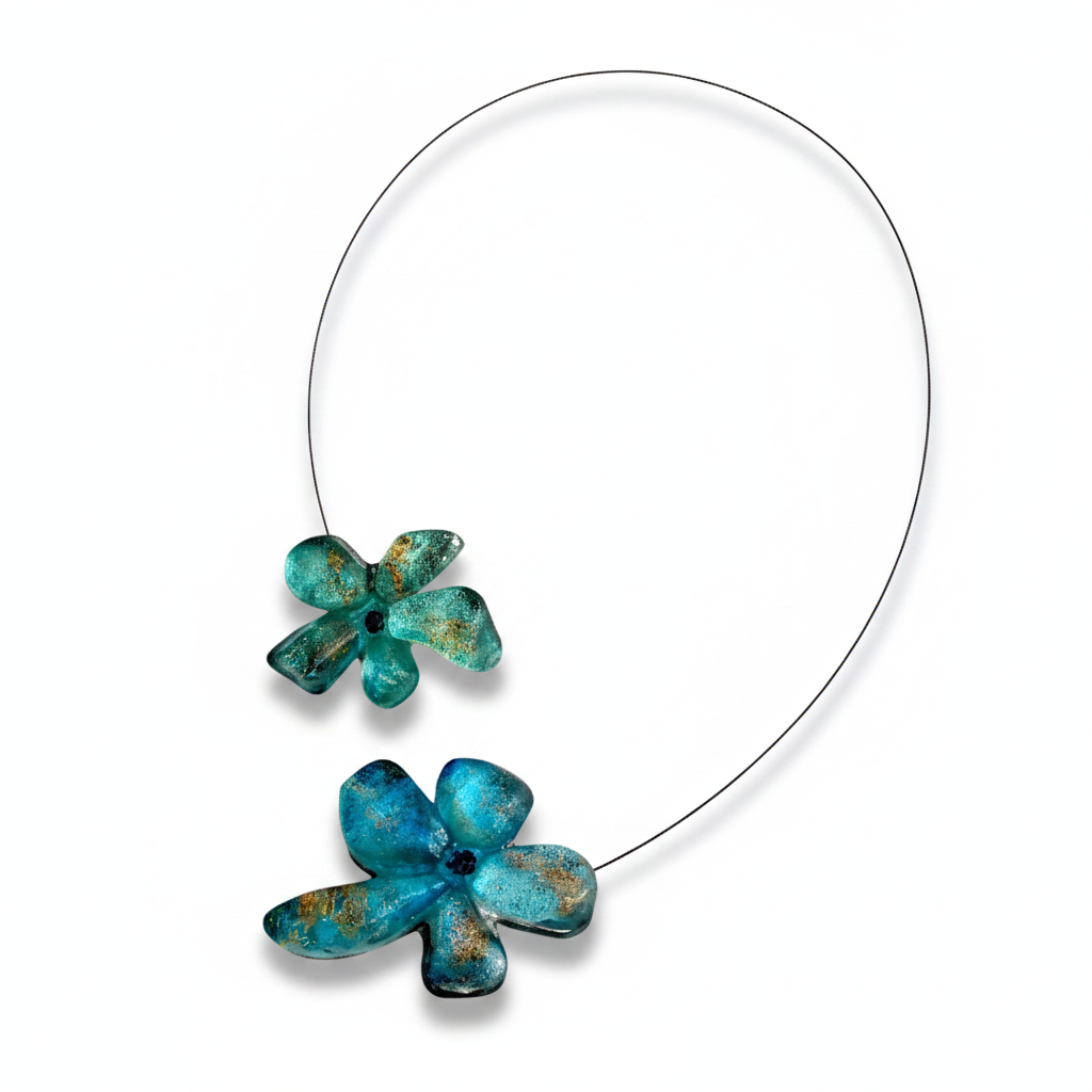 Collier en résine bleu vert avec reflets irisés, cable acier noir. Détail, fermoir aimanté à l'avant inséré dans les fleurs.