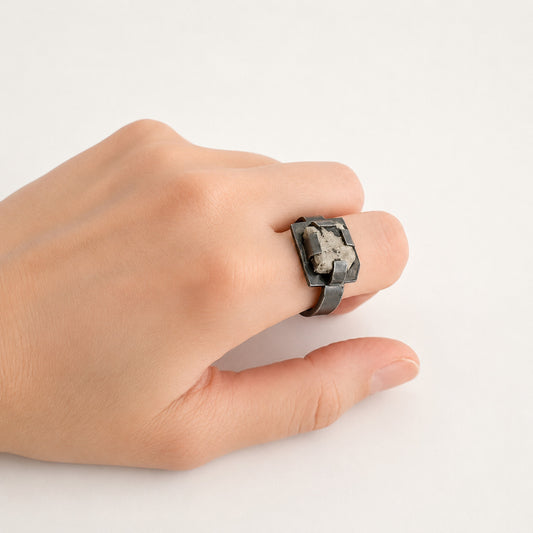 Détail bague contemporaine en argent oxydé et jaspe dalmatien. Quatre griffes plates maintiennent la pierre tout en laissant largement apparaître sa matière, et son dessin naturel.
