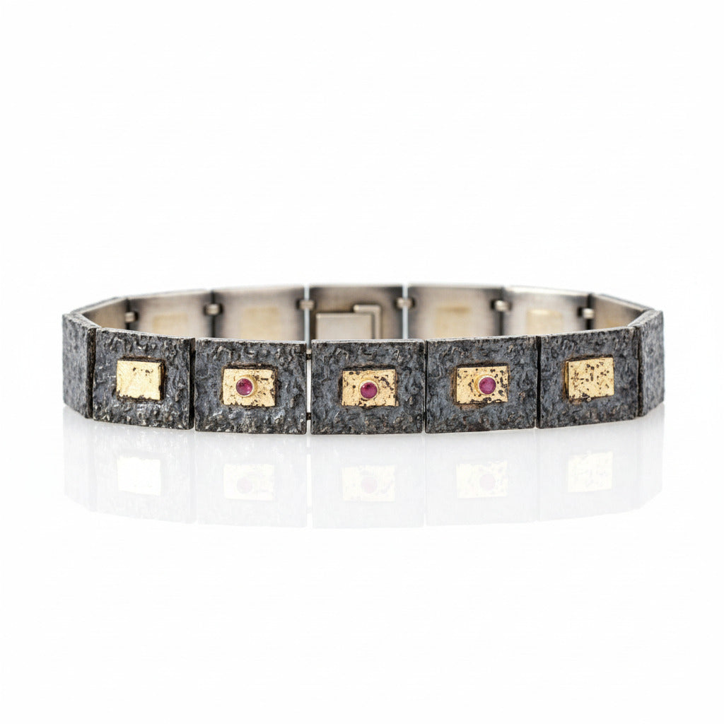 Bracelet articulé argent patiné, composé de 13 éléments rectangulaires, ornés de 5 rectangles or jaune et 3 rubis sertis. 