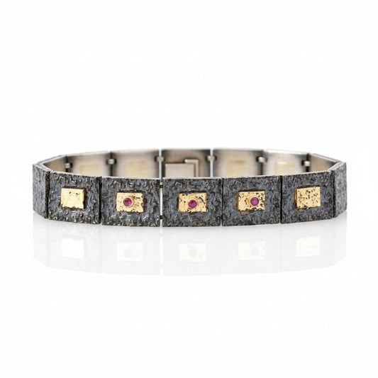 Bracelet articulé argent patiné, composé de 13 éléments rectangulaires, ornés de 5 rectangles or jaune et 3 rubis sertis. 