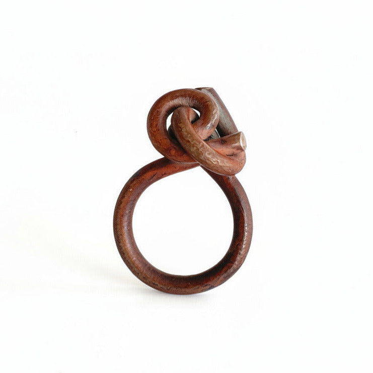 Bague graphique avec noeud sur le dessus en titane forgé, patine effet bois, reflets dorées. pièce 2019 façonnée par Marianne Anselin.